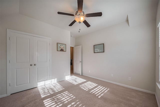 unfurnished bedroom featuring carpet floors, a closet, baseboards, and a ceiling fan