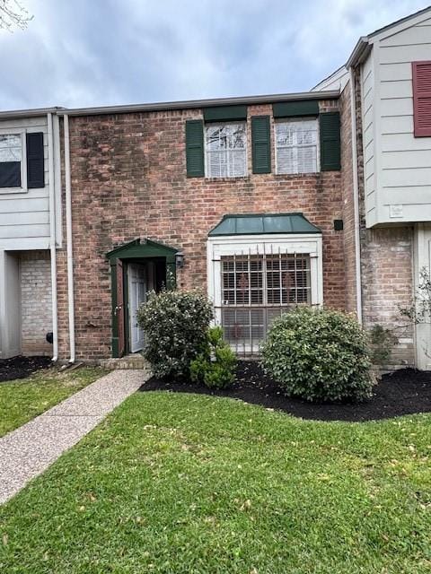 multi unit property featuring brick siding and a front yard