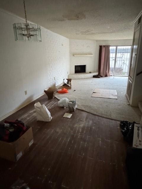 unfurnished living room featuring a large fireplace, an inviting chandelier, and wood finished floors