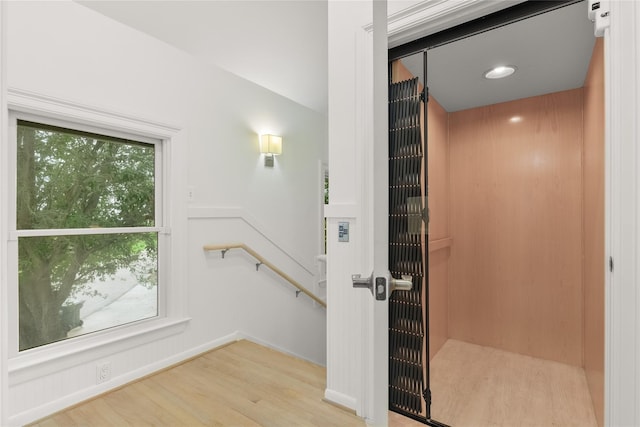 bathroom with elevator, baseboards, and wood finished floors