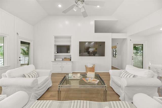 living area with lofted ceiling, wood finished floors, a ceiling fan, and built in features