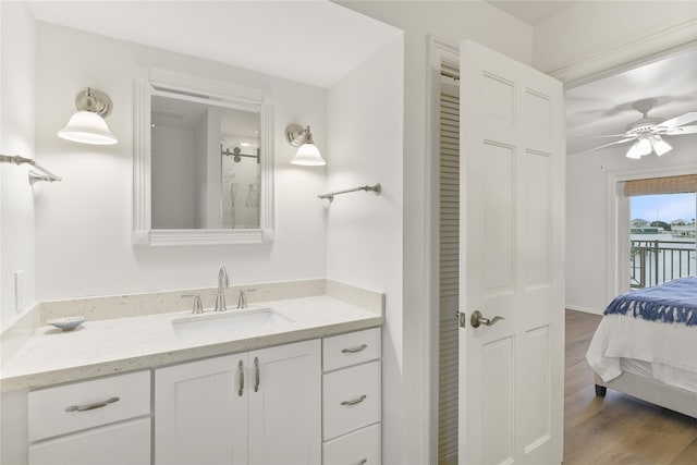 ensuite bathroom with ceiling fan, ensuite bath, wood finished floors, and vanity