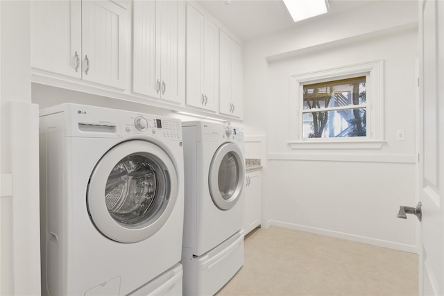 washroom with cabinet space, baseboards, and separate washer and dryer