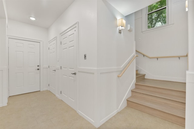 tiled foyer entrance with stairs and wainscoting