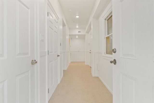 hallway featuring light tile patterned floors, visible vents, a decorative wall, and recessed lighting