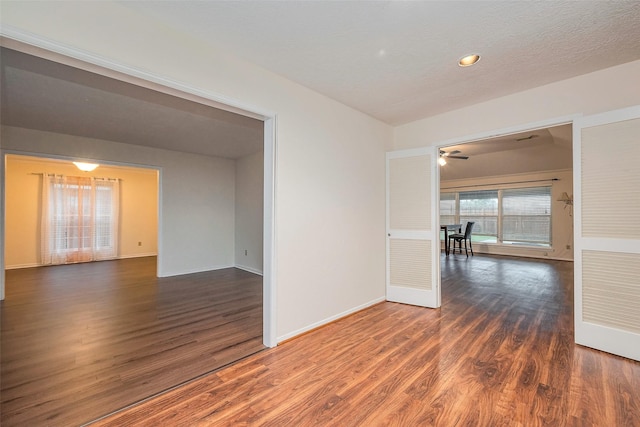 unfurnished room with a textured ceiling, baseboards, and wood finished floors