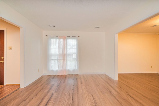 spare room featuring baseboards, visible vents, and light wood finished floors