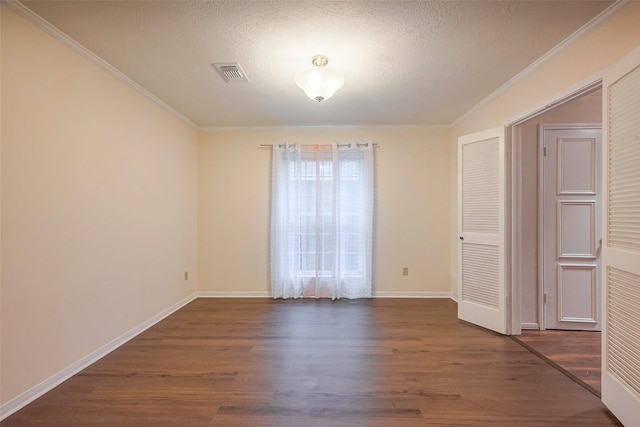 empty room with ornamental molding, visible vents, and wood finished floors