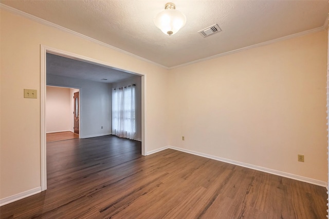 empty room featuring dark wood-type flooring, visible vents, ornamental molding, and baseboards