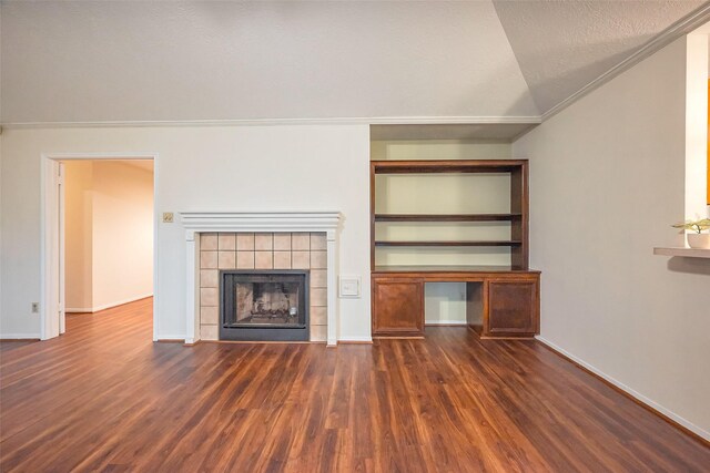 unfurnished living room with lofted ceiling, a textured ceiling, wood finished floors, a tile fireplace, and baseboards