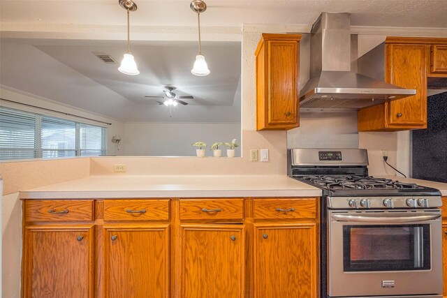 kitchen featuring wall chimney exhaust hood, stainless steel gas range oven, brown cabinets, and light countertops