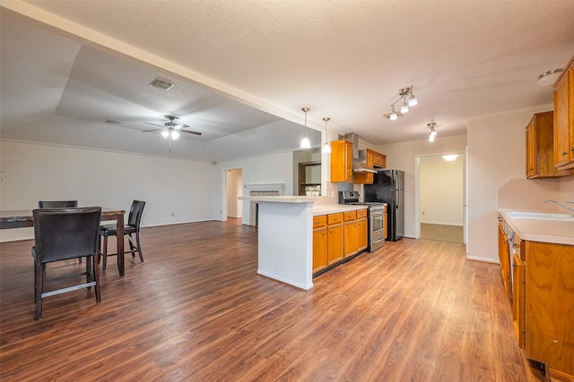 kitchen featuring brown cabinets, visible vents, dark wood-type flooring, a sink, and stainless steel gas range oven