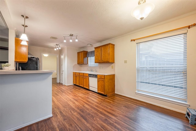 kitchen featuring brown cabinets, dark wood-type flooring, freestanding refrigerator, white dishwasher, and a sink