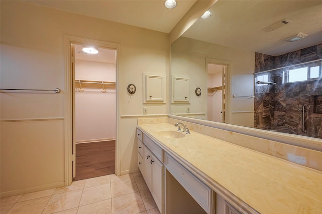 bathroom with a stall shower, a walk in closet, visible vents, and vanity