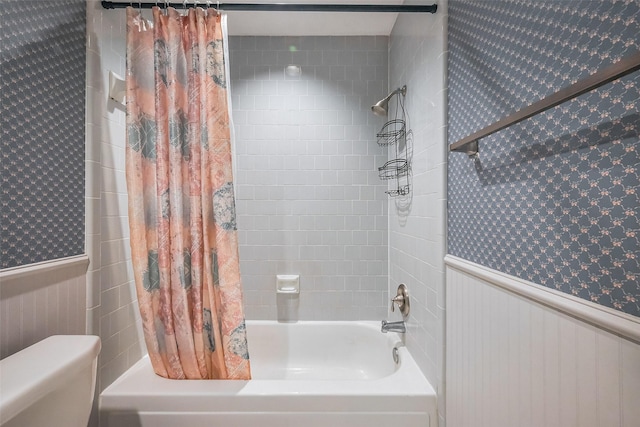 full bath featuring wallpapered walls, shower / bathtub combination with curtain, and wainscoting