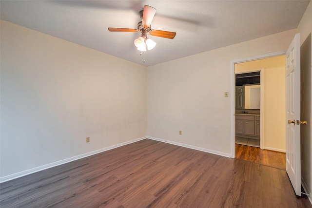 empty room featuring dark wood-style floors, baseboards, and a ceiling fan