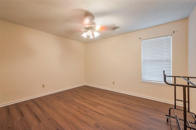 unfurnished room featuring baseboards, ceiling fan, visible vents, and wood finished floors