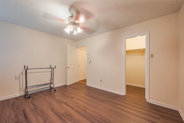 unfurnished bedroom with a spacious closet, baseboards, and wood finished floors