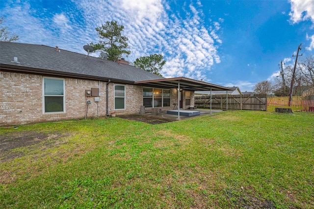 back of property featuring a lawn, roof with shingles, fence, a patio area, and brick siding