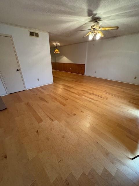 unfurnished living room with visible vents, light wood-style floors, ceiling fan, and a textured ceiling