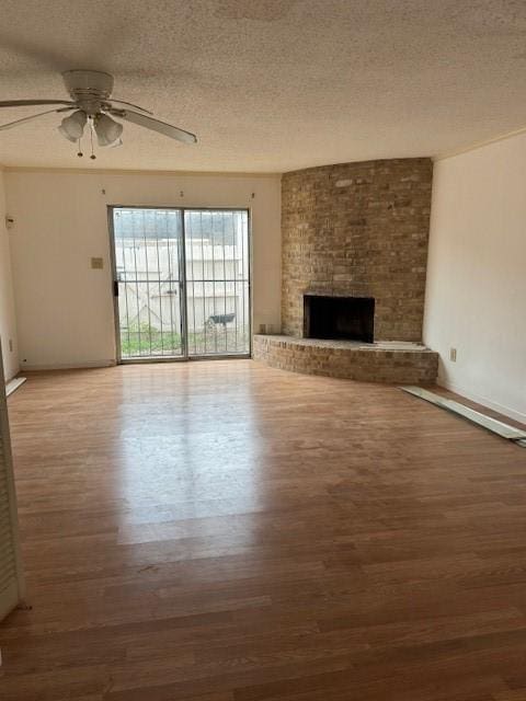 unfurnished living room with a fireplace, a textured ceiling, ceiling fan, and wood finished floors