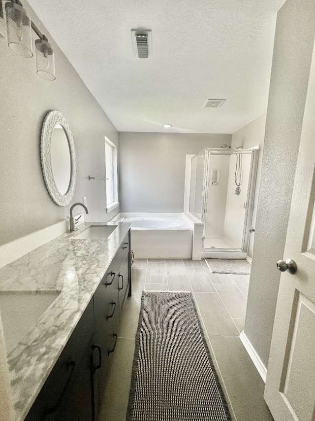 full bathroom featuring double vanity, a sink, a shower stall, a textured ceiling, and a bath