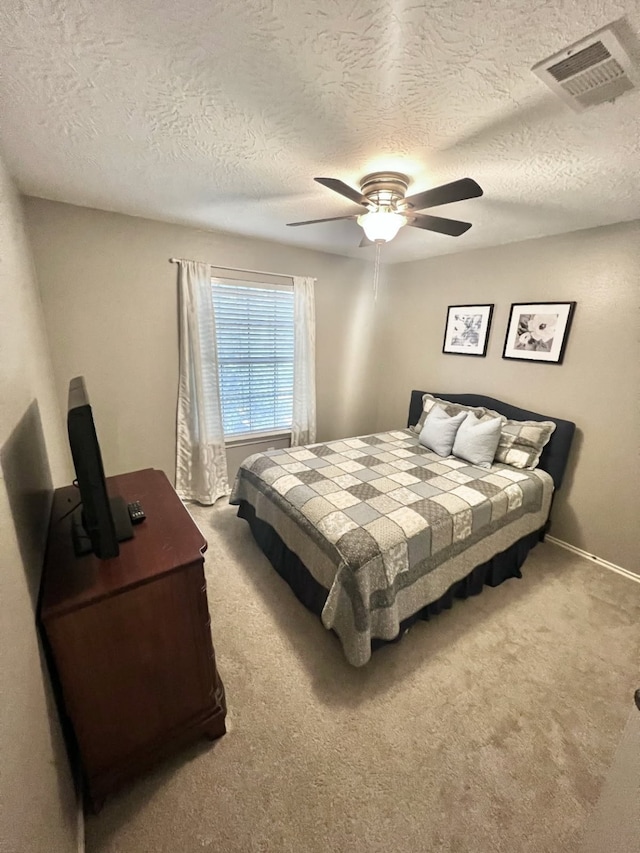 bedroom featuring baseboards, visible vents, ceiling fan, a textured ceiling, and carpet flooring