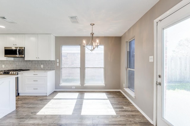 kitchen with stainless steel appliances, light wood-type flooring, light countertops, and white cabinetry