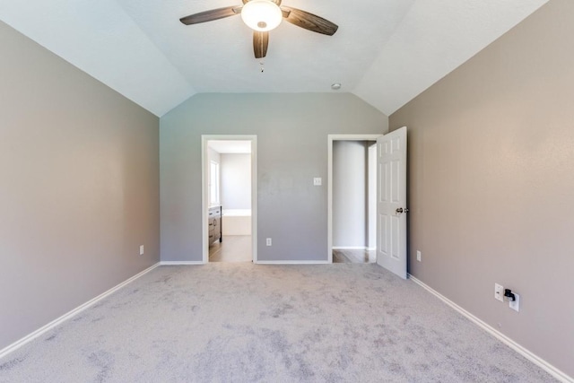 unfurnished bedroom with ensuite bathroom, carpet flooring, a ceiling fan, baseboards, and vaulted ceiling