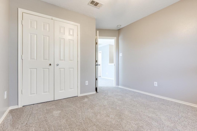 unfurnished bedroom with carpet floors, a closet, visible vents, and baseboards