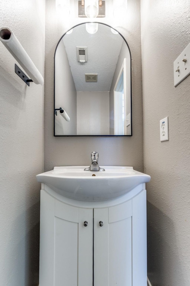 bathroom with visible vents, a textured wall, and vanity