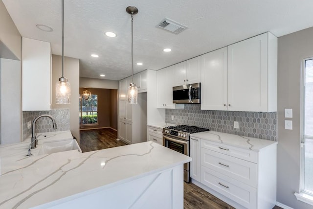 kitchen featuring light stone counters, appliances with stainless steel finishes, a sink, and visible vents