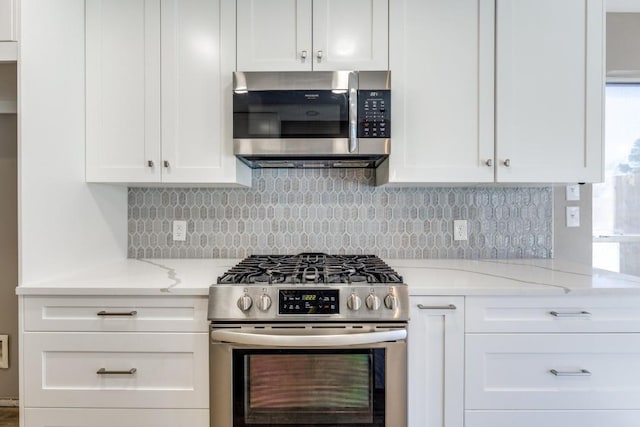 kitchen featuring stainless steel appliances, white cabinetry, decorative backsplash, and light stone countertops