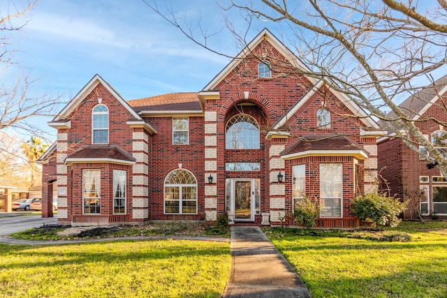 traditional-style house with a shingled roof, a front yard, and brick siding