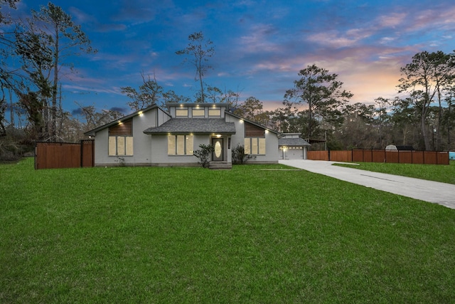 mid-century inspired home featuring a front yard, concrete driveway, and fence