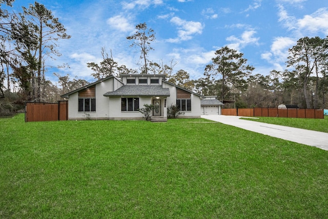 mid-century inspired home with roof with shingles, driveway, a front lawn, and fence