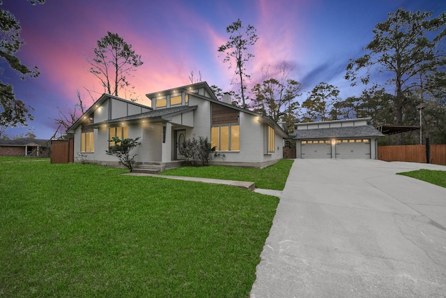 mid-century modern home with a garage, brick siding, fence, driveway, and a front lawn