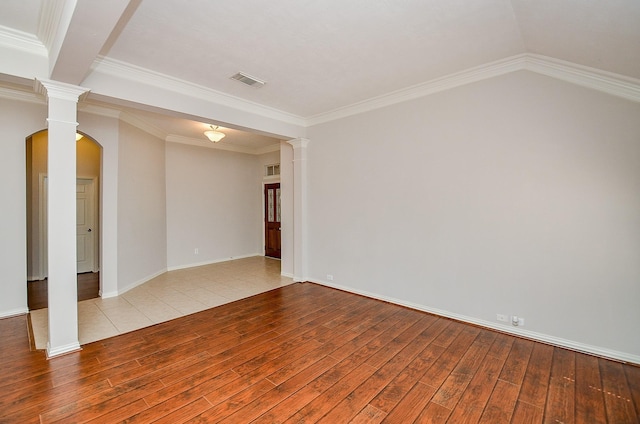 empty room featuring ornate columns, crown molding, visible vents, and wood finished floors