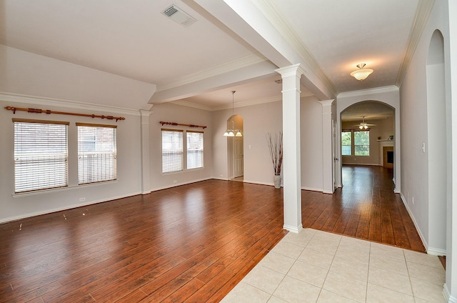 empty room featuring plenty of natural light, a fireplace, visible vents, and ornate columns