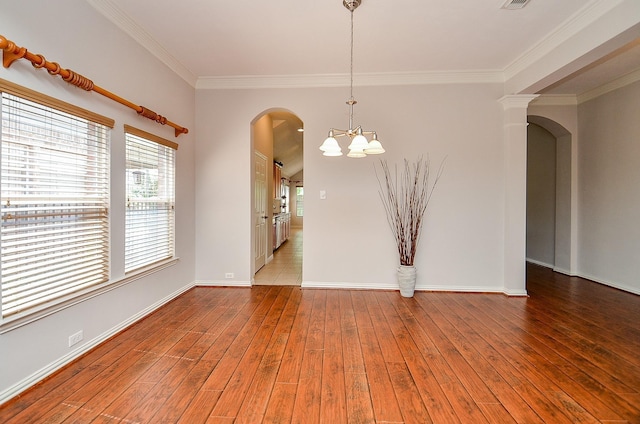 spare room featuring arched walkways, crown molding, wood-type flooring, a chandelier, and baseboards