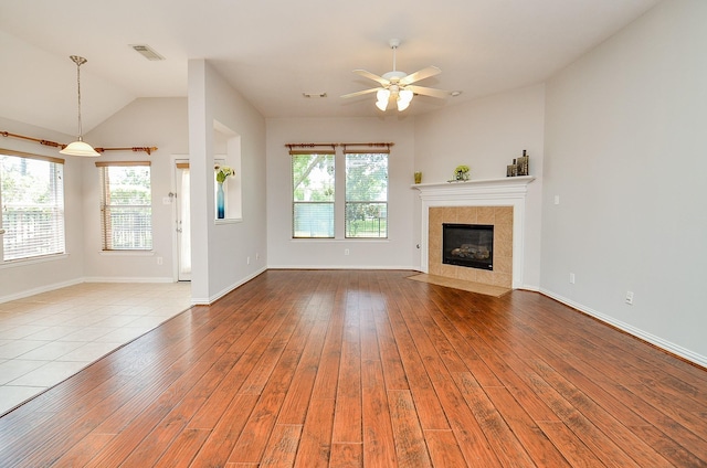 unfurnished living room with a healthy amount of sunlight, visible vents, hardwood / wood-style floors, and a tile fireplace