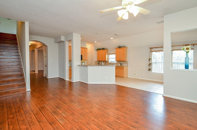 unfurnished living room with a healthy amount of sunlight, light wood finished floors, and stairs