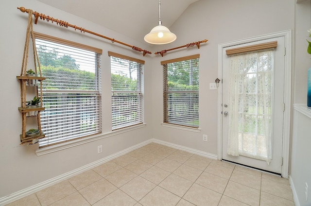 doorway featuring light tile patterned floors, lofted ceiling, and baseboards