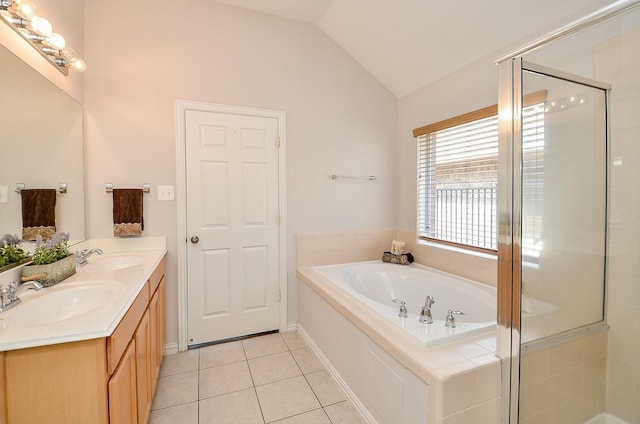 bathroom with tile patterned flooring, vaulted ceiling, a garden tub, and a sink