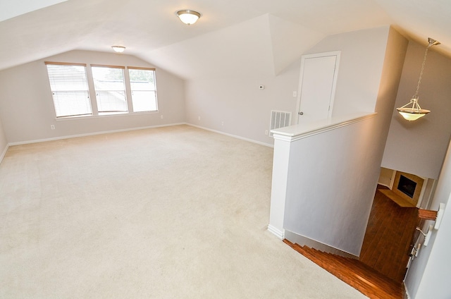 additional living space featuring visible vents, vaulted ceiling, light carpet, and baseboards