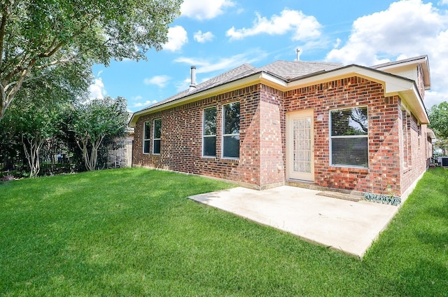 back of property featuring brick siding, a shingled roof, fence, a lawn, and a patio area