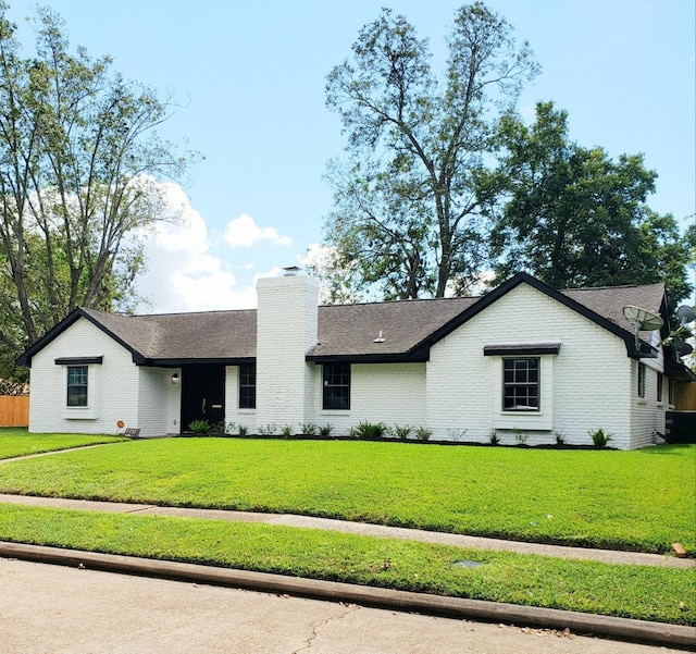 view of front of house with a front lawn, a chimney, and brick siding