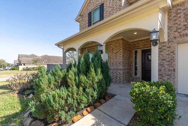 view of exterior entry featuring covered porch and brick siding