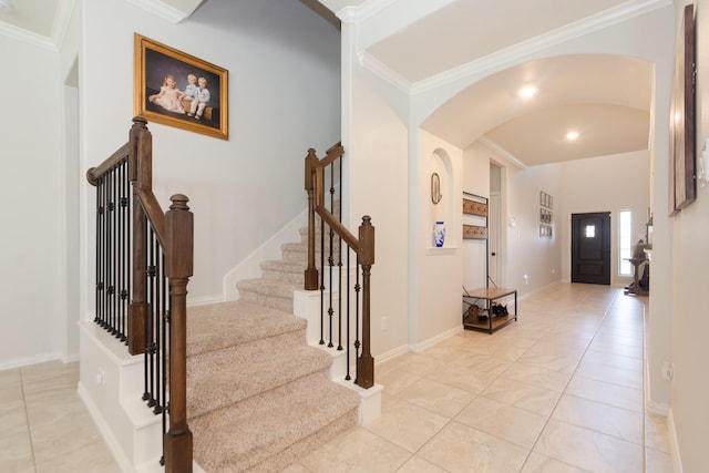 entrance foyer featuring ornamental molding, arched walkways, baseboards, and light tile patterned floors