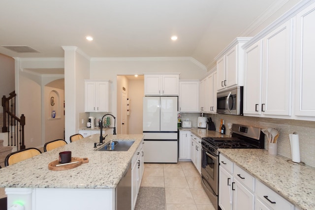 kitchen with appliances with stainless steel finishes, an island with sink, a sink, and white cabinetry